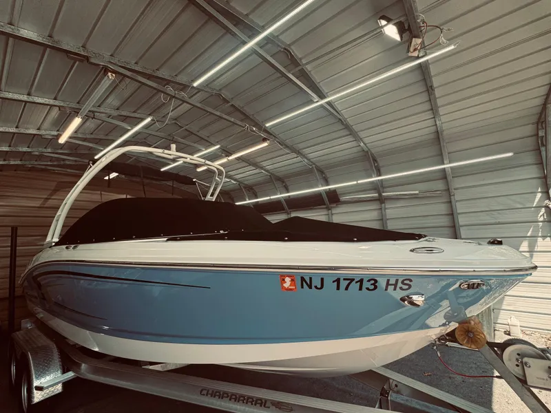 Slide: The Image of 2023 Chaparral 21 SSi OB boat in a garage, blue and white exterior. - 3