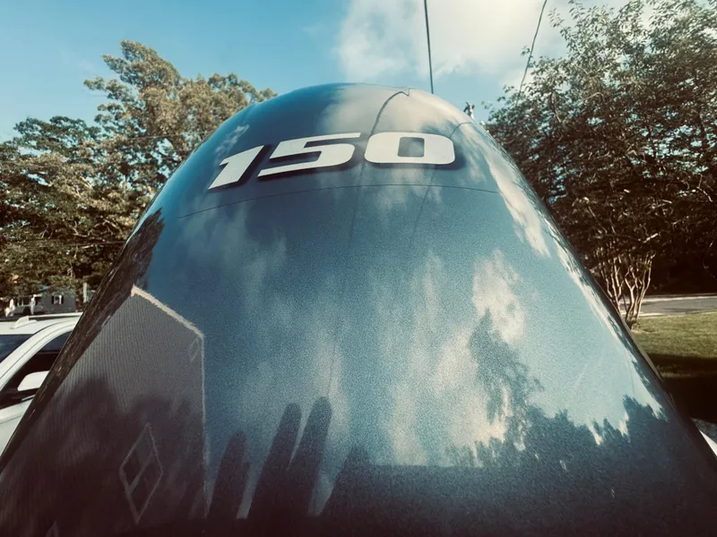 Slide: The Image of Close-up of 2023 Chaparral 21 SSi OB outboard motor with '150' label, reflecting sky and trees. - 34