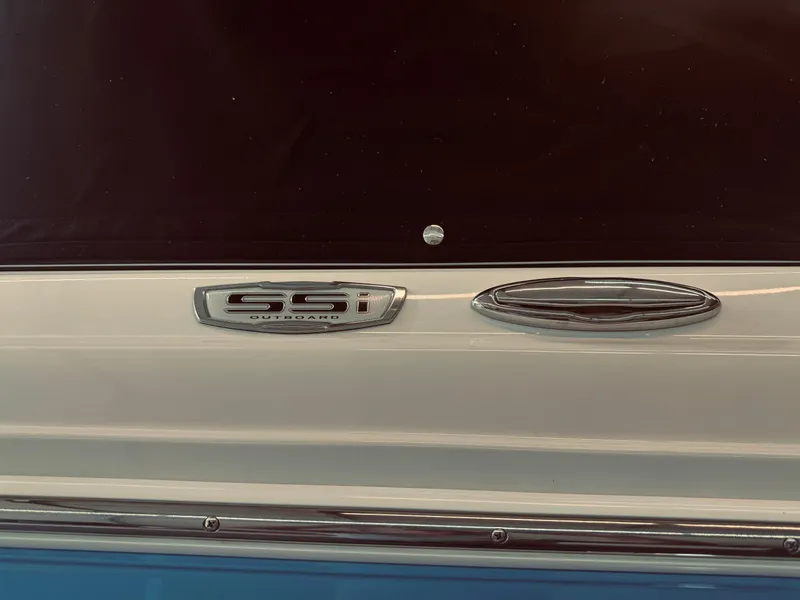 Slide: The Image of 2023 Chaparral 21 SSi OB boat emblem on a sleek white and blue exterior. - 7
