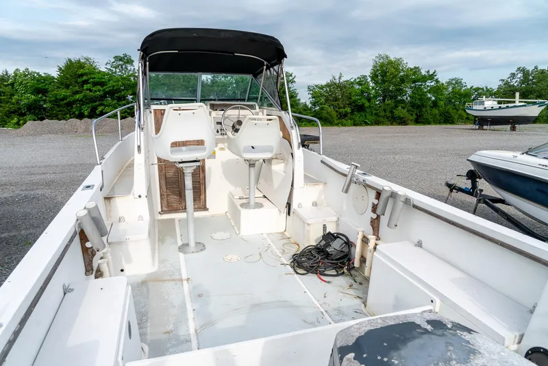Slide: The Image of 1986 Aquasport 250 Express Fisherman boat with open deck and seating, parked outdoors. - 15