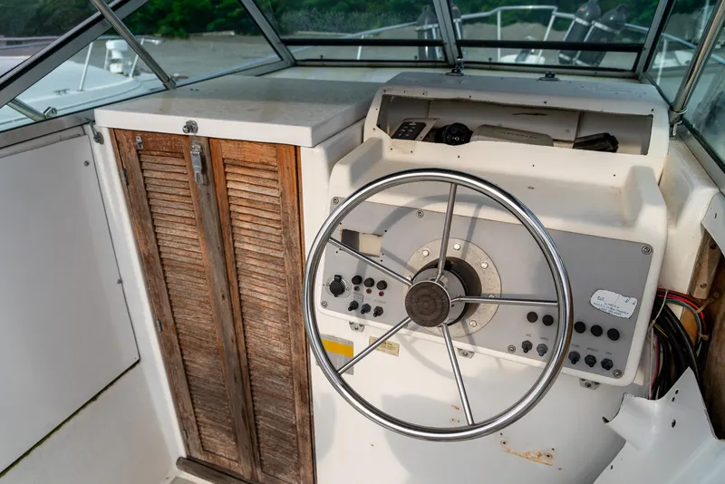 Slide: The Image of 1986 Aquasport 250 Express Fisherman boat helm with wooden cabinet and steering wheel. - 19