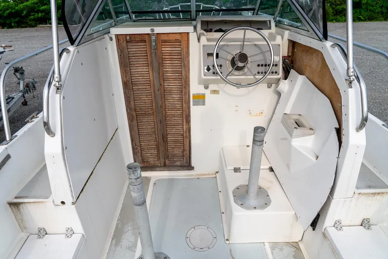 Slide: The Image of 1986 Aquasport 250 Express Fisherman boat cockpit with steering wheel and wooden door. - 23