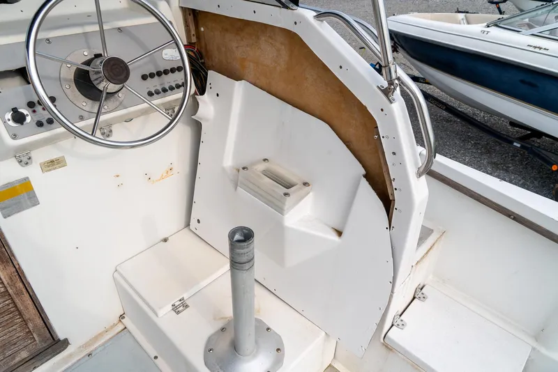 Slide: The Image of 1986 Aquasport 250 Express Fisherman boat cockpit with steering wheel and seating area. - 27