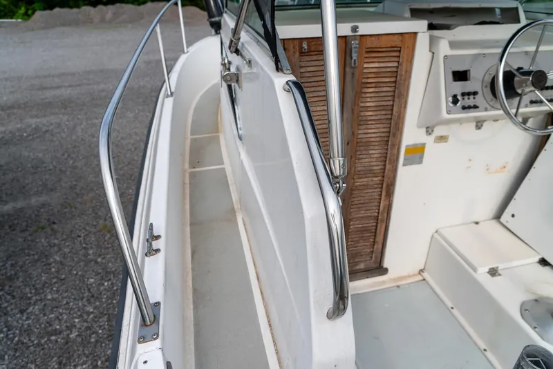 Slide: The Image of 1986 Aquasport 250 Express Fisherman boat interior with steering wheel and wooden cabinet. - 29