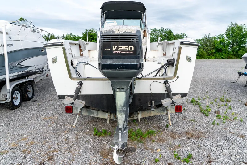 Slide: The Image of 1986 Aquasport 250 Express Fisherman boat with V250 outboard motor, parked on gravel. - 8