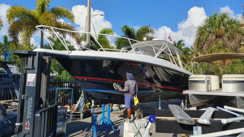 Slide: The Image of 2002 Intrepid 377 Walkaround boat being polished at a marina with palm trees. - 1