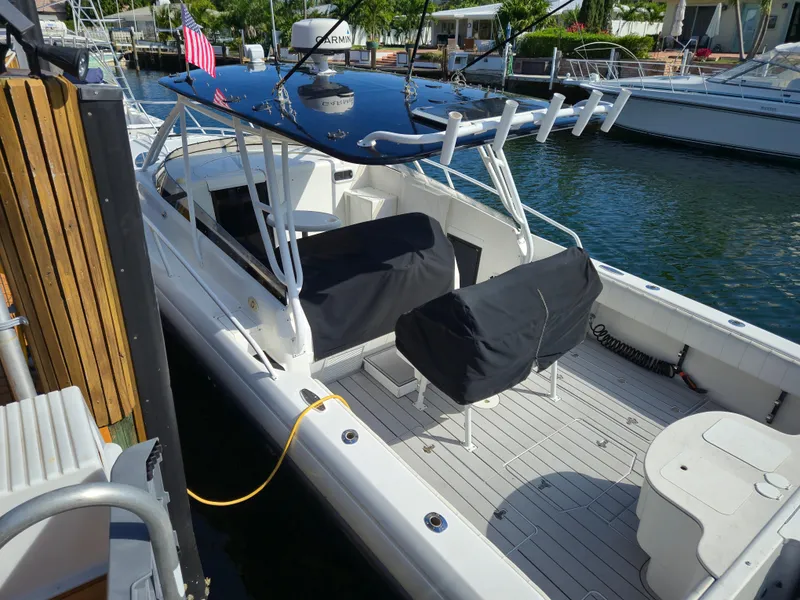 Slide: The Image of 2002 Intrepid 377 Walkaround boat docked, featuring covered seating and fishing rod holders. - 10