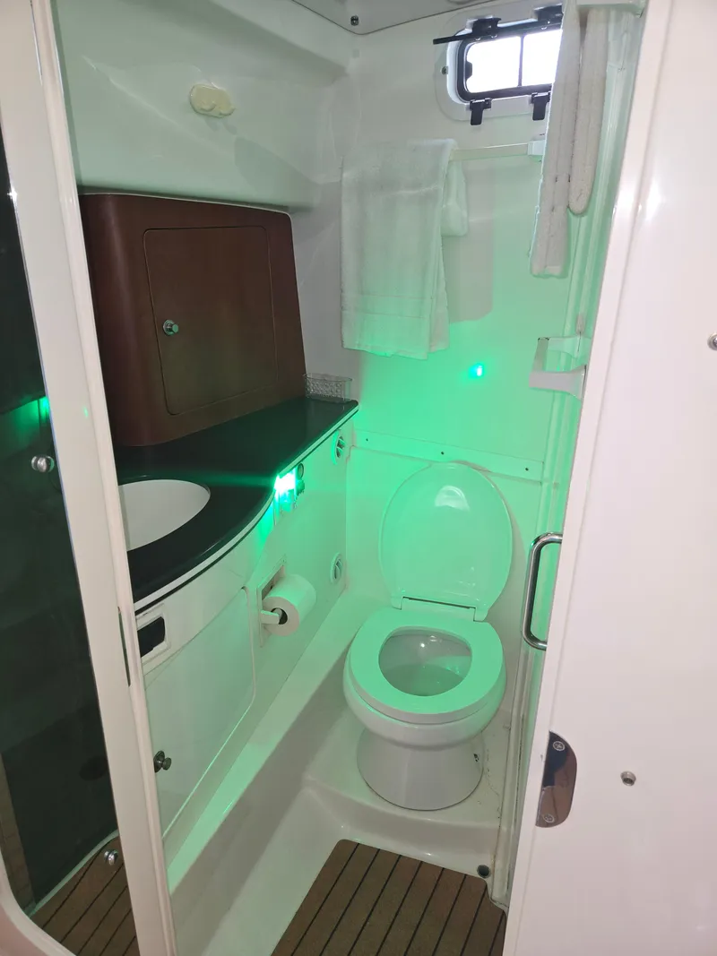 Slide: The Image of 2002 Intrepid 377 Walkaround boat bathroom with toilet, sink, and green lighting. - 16