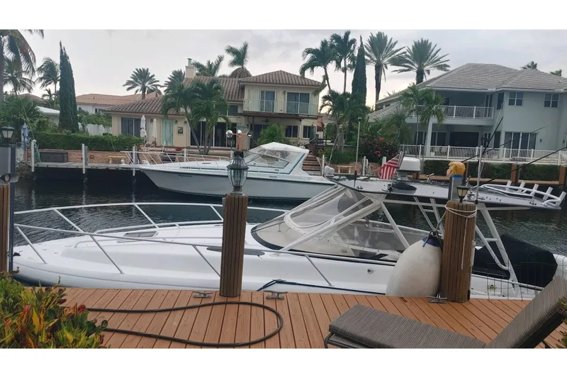 Slide: The Image of 2002 Intrepid 377 Walkaround boat docked near waterfront homes with palm trees. - 22