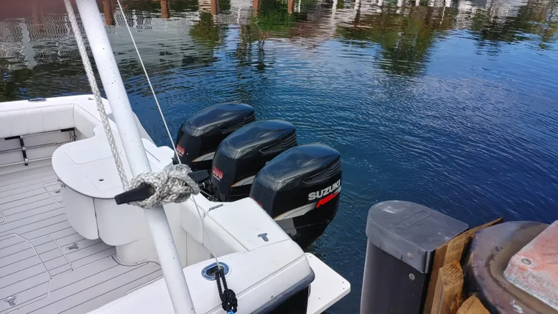 Slide: The Image of 2002 Intrepid 377 Walkaround boat with triple Suzuki outboard motors docked on calm water. - 7