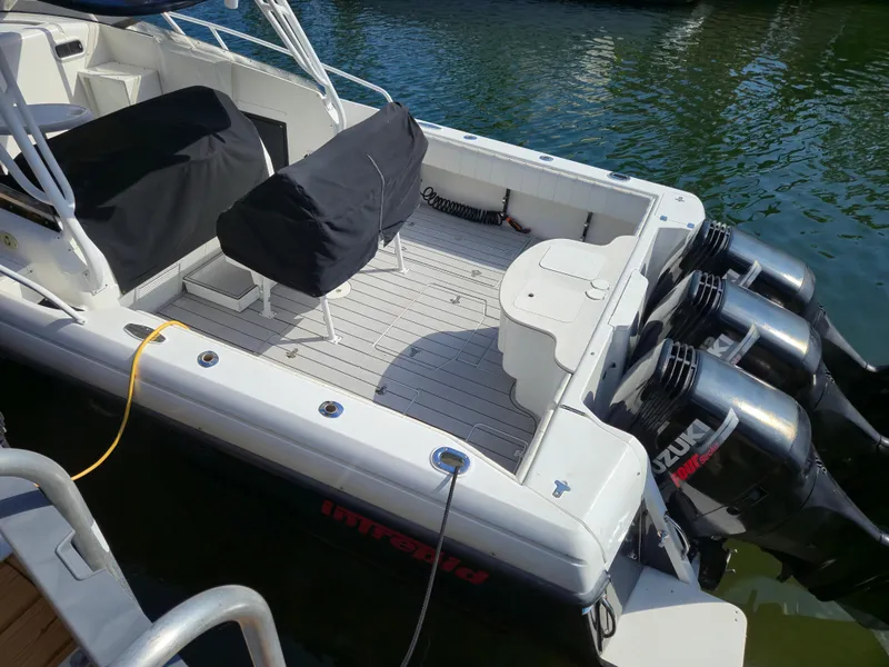 Slide: The Image of 2002 Intrepid 377 Walkaround boat with triple Suzuki outboard motors docked in water. - 9