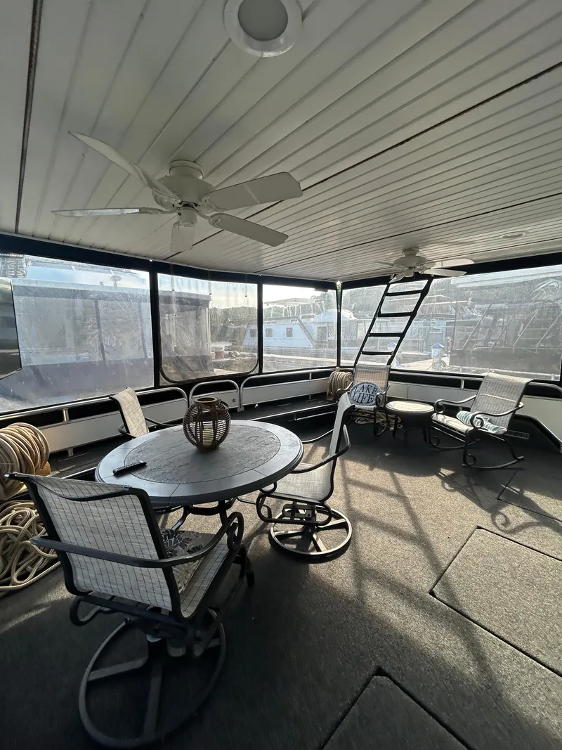 Slide: The Image of Spacious 2001 Fantasy houseboat interior with seating, table, and ceiling fans. - 2