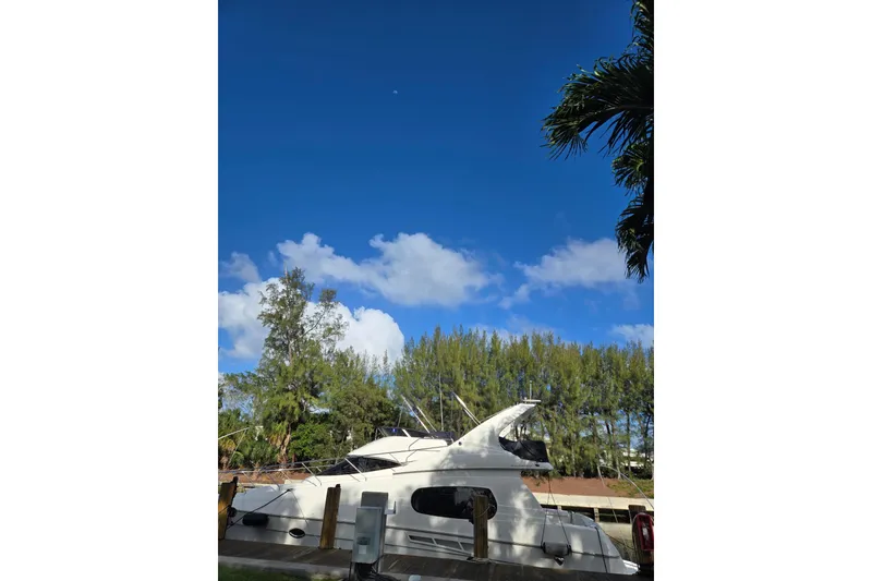 Slide: The Image of 2001 Silverton 410 Sport Bridge yacht docked at a marina under clear blue skies. - 11