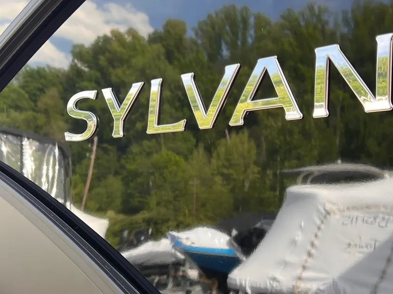 Slide: The Image of Sylvan L3 CLZ DH WT 2025 boat with reflective logo, surrounded by trees and covered boats. - 30