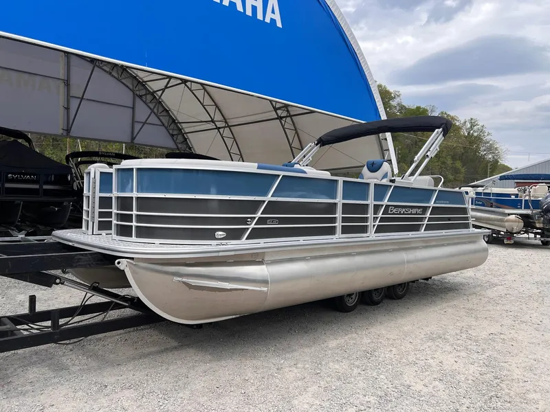 Slide: The Image of 2025 Berkshire LE Series 24UL LE pontoon boat on trailer, parked outdoors. - 1