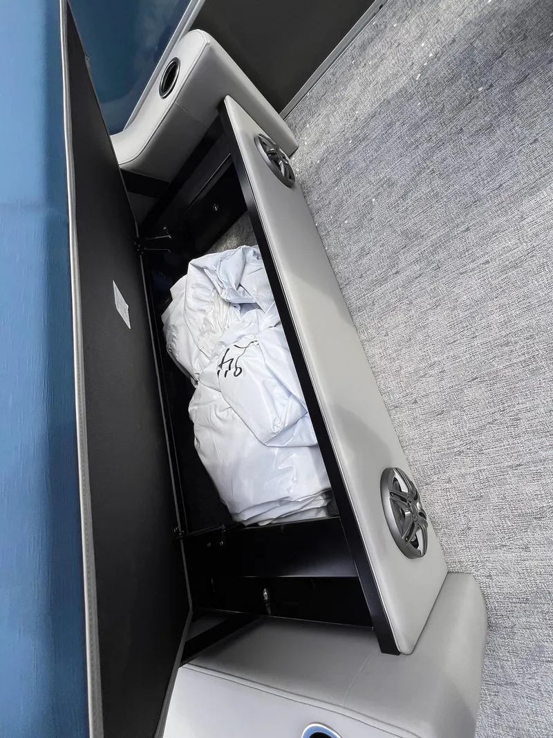 Slide: The Image of Open storage compartment in 2025 Berkshire LE Series 24UL LE boat, revealing interior contents. - 27