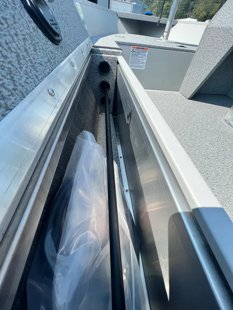 Slide: The Image of 2024 Starcraft Patriot 16 SC boat interior storage compartment with rod holder and textured finish. - 11
