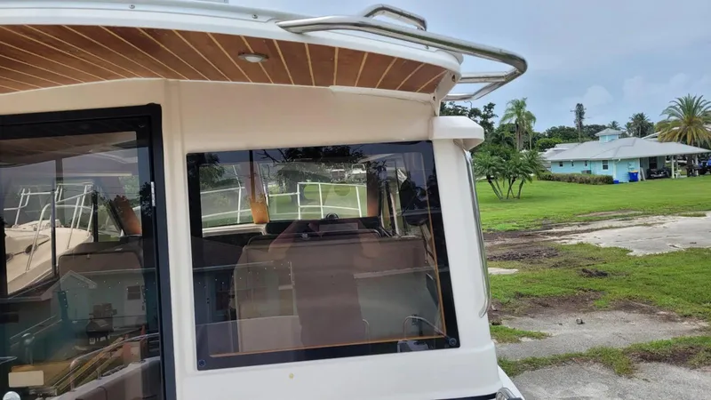 Slide: The Image of 2021 Cutwater C-28 boat docked near a grassy area with trees and a house. - 12