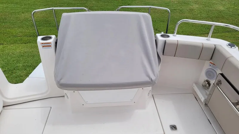 Slide: The Image of 2021 Cutwater C-28 boat deck with covered seating and railing, set against a grassy background. - 16