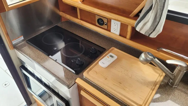Slide: The Image of Modern kitchen area in a 2021 Cutwater C-28 boat with stove and cutting board. - 21