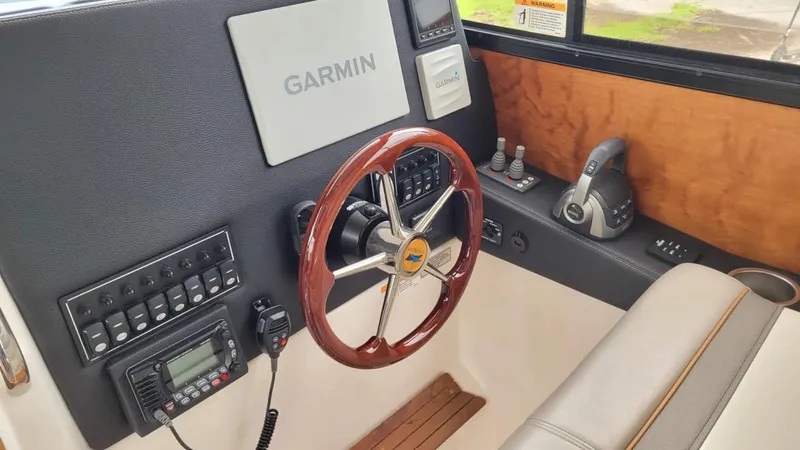Slide: The Image of 2021 Cutwater C-28 helm with Garmin navigation, wooden steering wheel, and control panel. - 24