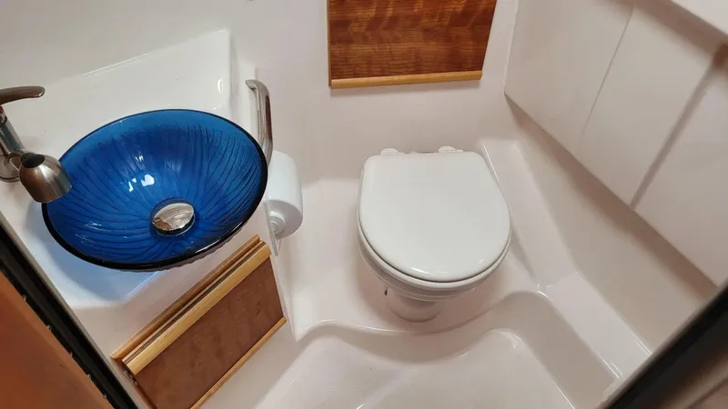 Slide: The Image of Compact bathroom in 2021 Cutwater C-28 boat with blue glass sink and white toilet. - 29
