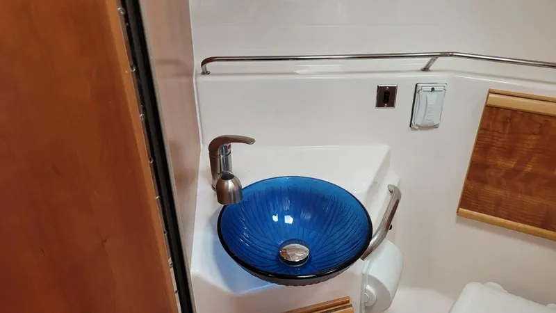 Slide: The Image of 2021 Cutwater C-28 bathroom with blue glass sink and modern fixtures. - 31