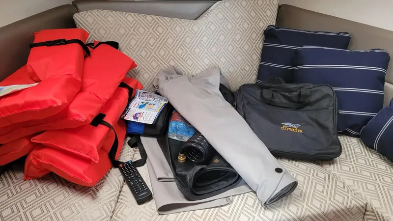 Slide: The Image of Interior of 2021 Cutwater C-28 with life jackets, remote, and accessories on a cushioned seat. - 32