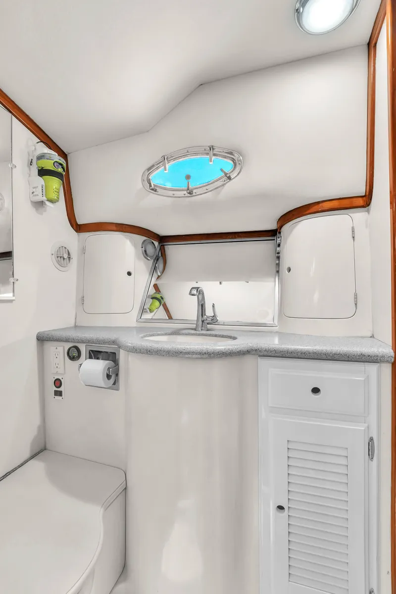 Slide: The Image of 2001 Mediterranean 38 Convertible yacht bathroom with sink, porthole, and storage cabinets. - 28