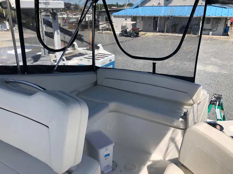 Slide: The Image of 2012 Bayliner 255 Cruiser interior with white seating and marina view. - 29
