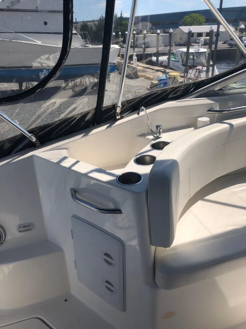 Slide: The Image of 2012 Bayliner 255 Cruiser interior with seating and cup holders, docked at a marina. - 42
