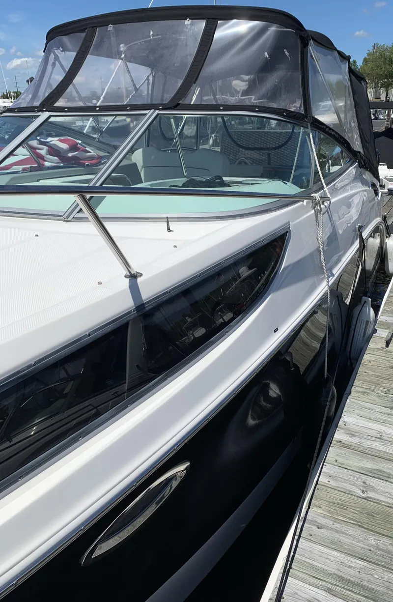 Slide: The Image of 2012 Bayliner 255 Cruiser docked, featuring sleek design and black canopy. - 48