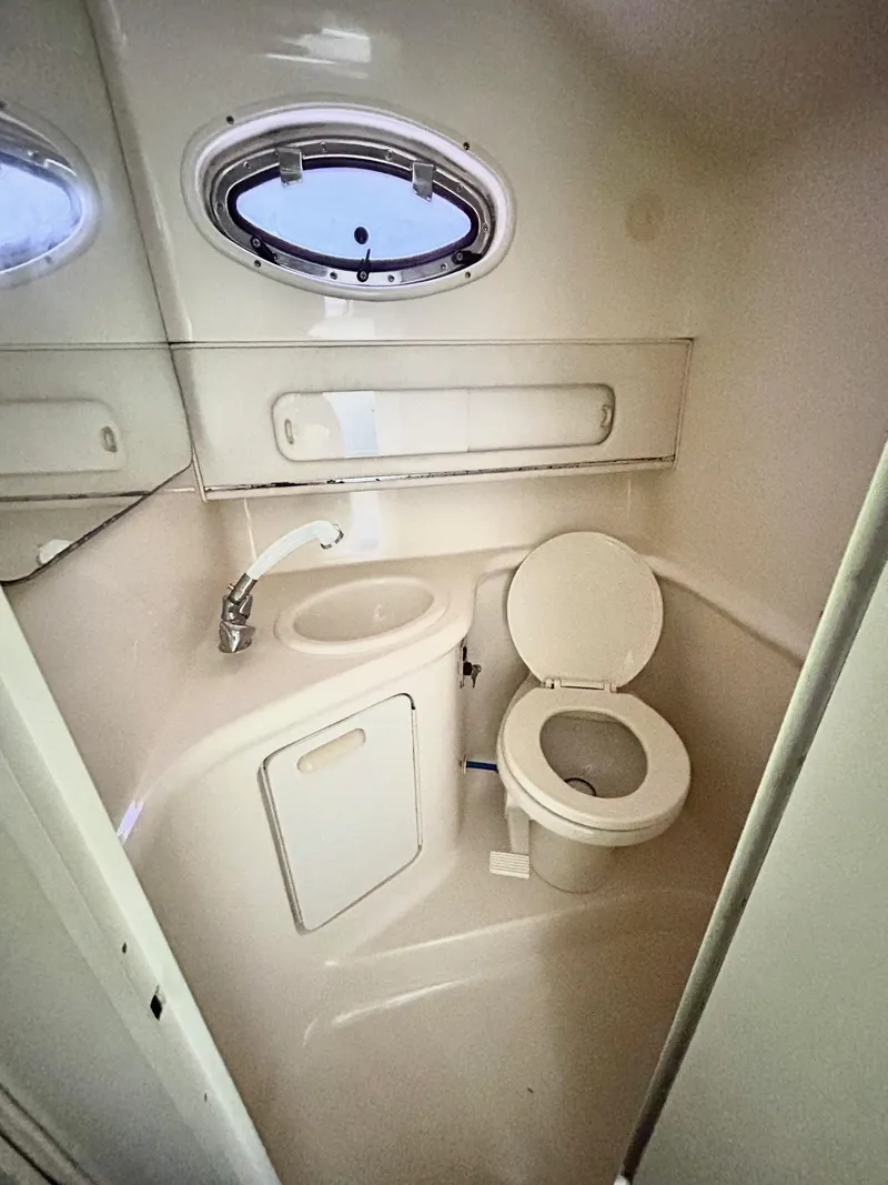 Slide: The Image of Compact bathroom in 1999 Sea Ray 270 Sundancer boat with toilet, sink, and porthole window. - 10
