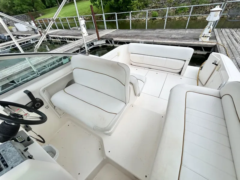 Slide: The Image of 1999 Sea Ray 270 Sundancer boat interior with white seating and dock view. - 16