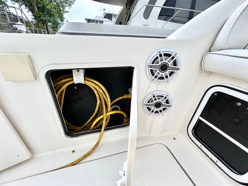 Slide: The Image of 1999 Sea Ray 270 Sundancer boat storage compartment with coiled yellow cable and speakers. - 17