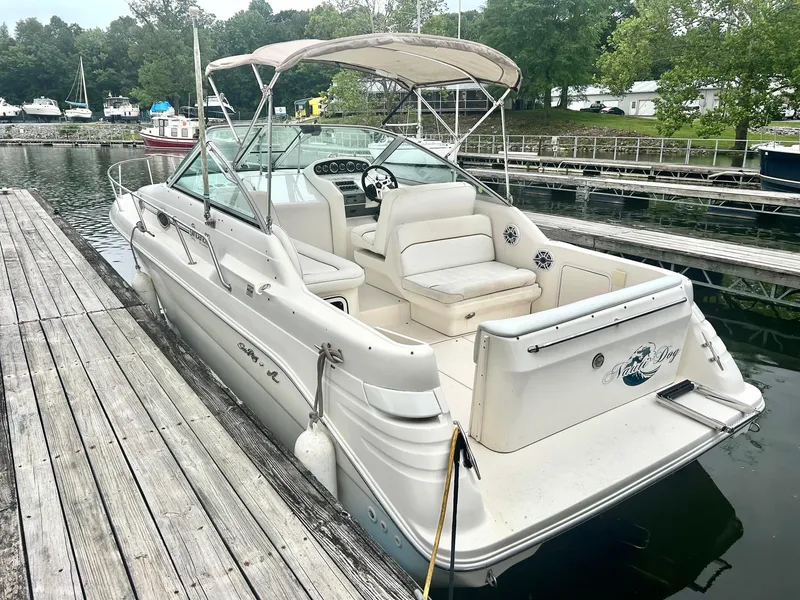 Slide: The Image of 1999 Sea Ray 270 Sundancer docked at a marina, featuring spacious seating and canopy. - 2
