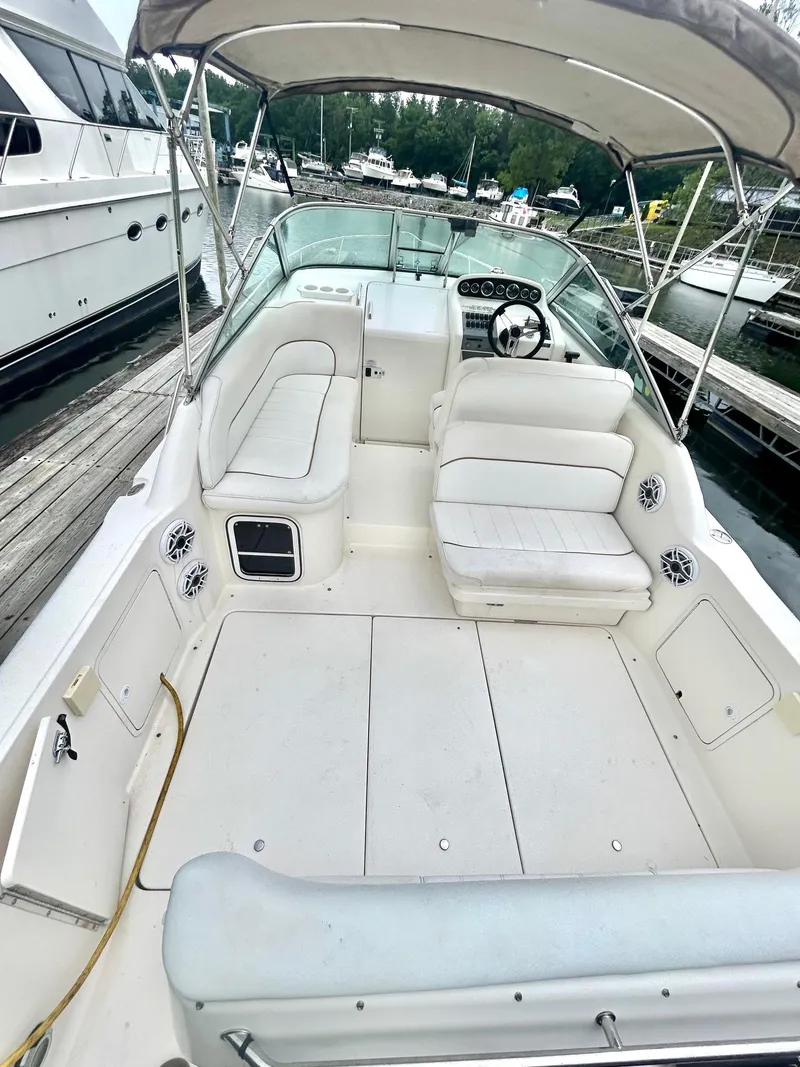 Slide: The Image of 1999 Sea Ray 270 Sundancer boat interior with white seating and canopy at marina. - 6