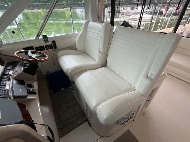 Slide: The Image of 2004 Sea Ray 390 Motor Yacht helm with white leather seats and wooden steering wheel. - 13