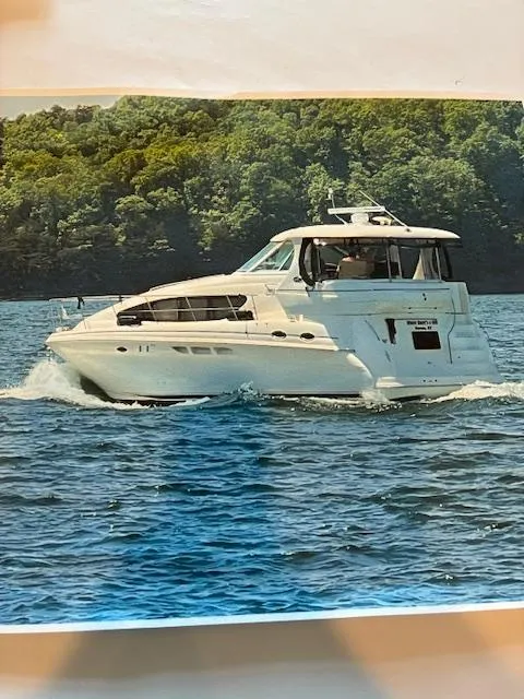 Slide: The Image of 2004 Sea Ray 390 Motor Yacht cruising on a lake with lush green forest backdrop. - 18