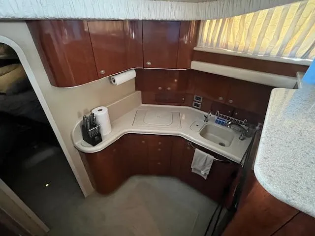 Slide: The Image of 2004 Sea Ray 390 Motor Yacht kitchen with wooden cabinets and compact sink area. - 26