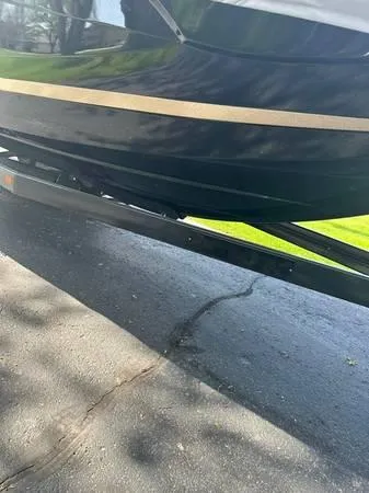 Slide: The Image of 2021 Centurion Ri265 boat on trailer, black hull with tan stripe, parked on pavement. - 11