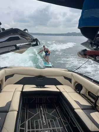 Slide: The Image of 2021 Centurion Ri265 boat with a person wakesurfing behind it on a lake. - 6