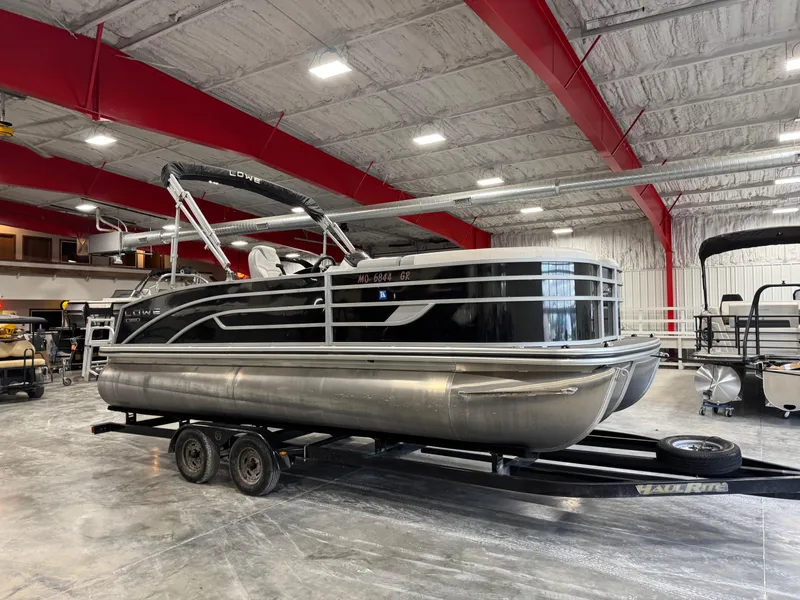 Slide: The Image of 2022 Lowe 210 SS pontoon boat in a spacious indoor showroom. - 2