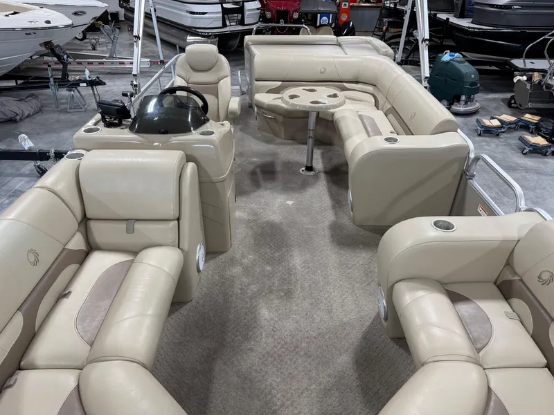 Slide: The Image of 2015 Lowe 210 SS pontoon boat interior with beige seating and central table. - 13