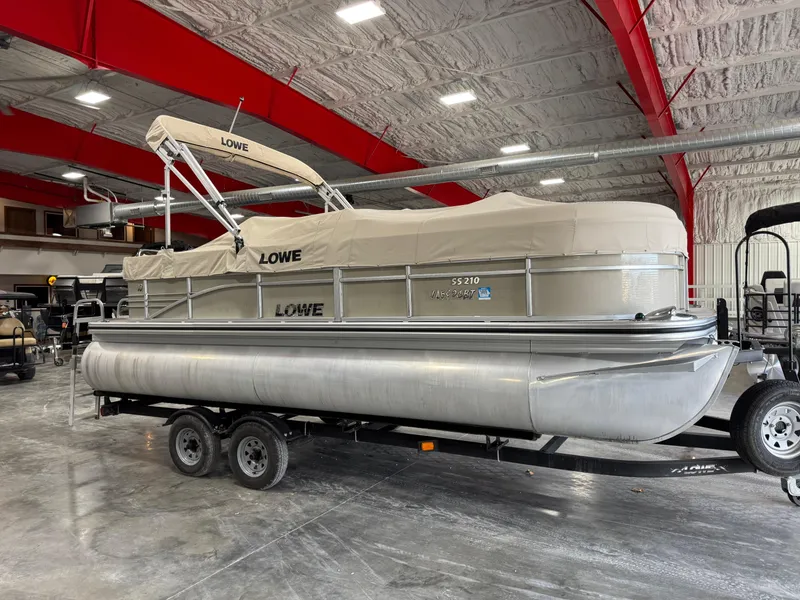 Slide: The Image of 2015 Lowe 210 SS pontoon boat with cover in a spacious indoor storage facility. - 14