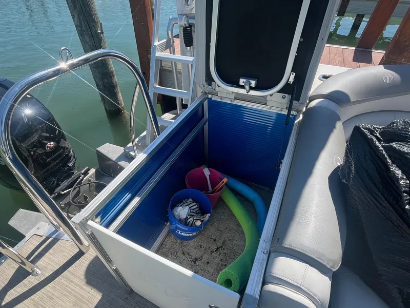 Slide: The Image of Open storage compartment on 2018 Tahoe Cascade 2585 CR boat with pool noodles and bucket. - 12