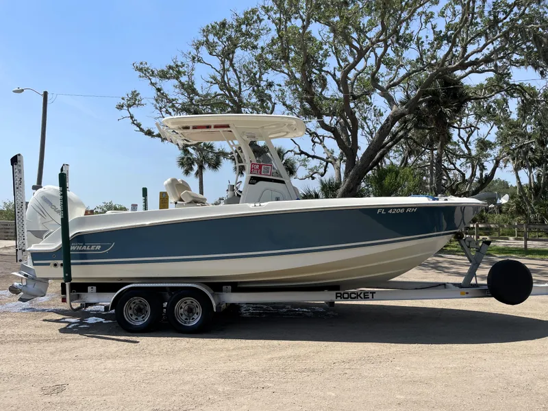 Slide: The Image of 2017 Boston Whaler 230 Outrage boat on trailer, parked outdoors. - 0