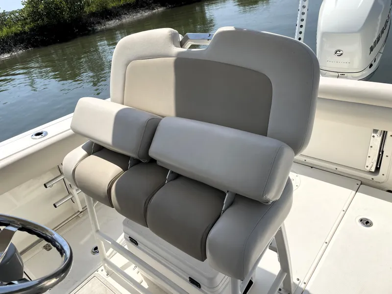 Slide: The Image of 2017 Boston Whaler 230 Outrage boat seating, featuring cushioned helm seats on a sunny day. - 11