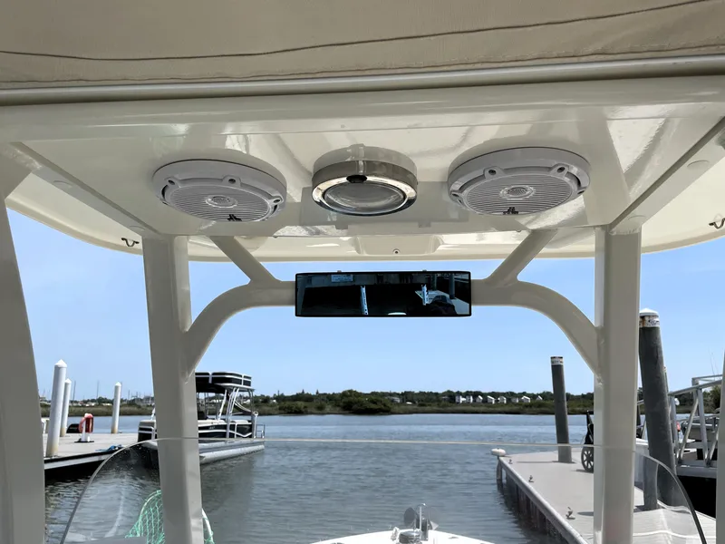 Slide: The Image of 2017 Boston Whaler 230 Outrage boat console with speakers and mirror, docked by the water. - 13