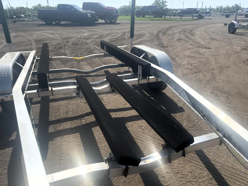 Slide: The Image of Boat trailer for 2017 Boston Whaler 230 Outrage on dirt lot with trucks in background. - 20